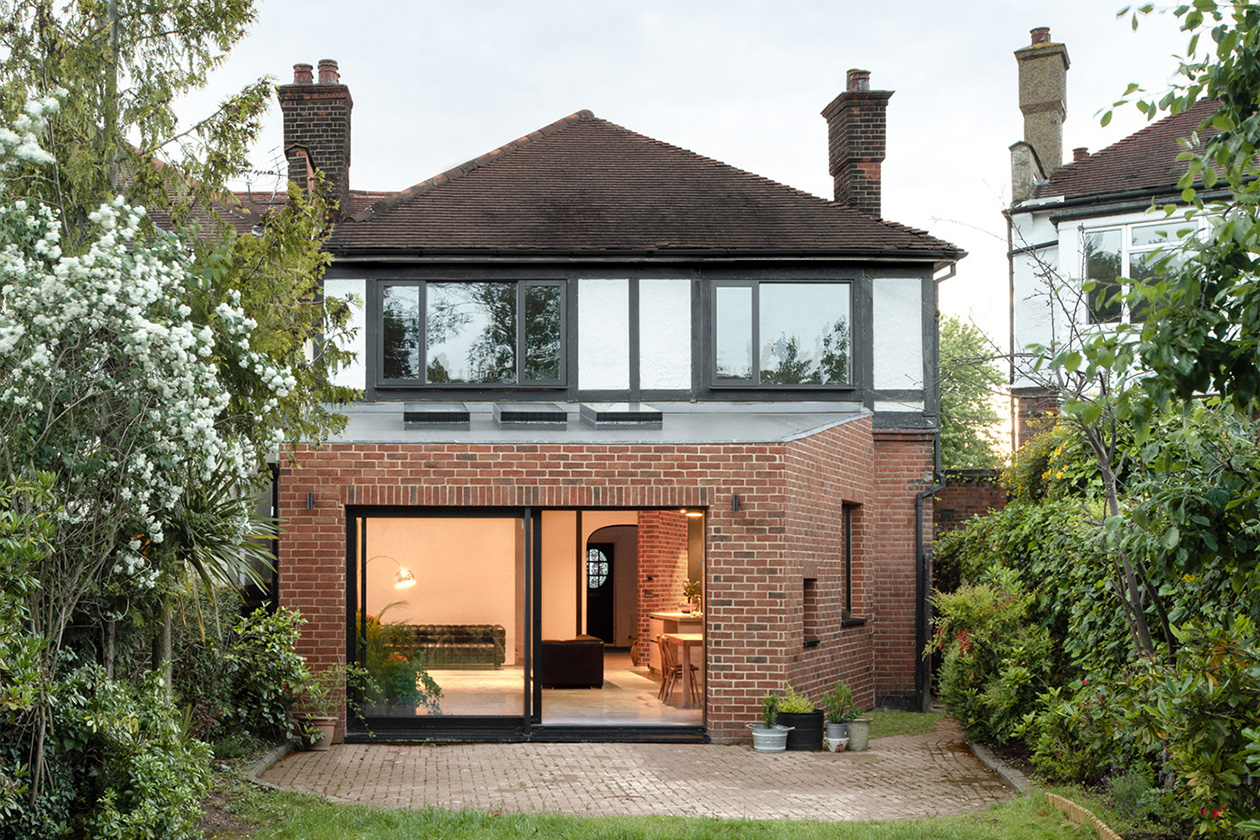 The rear of a semi detached house with a new red brick extension. The sliding doors are open to a welcoming interior