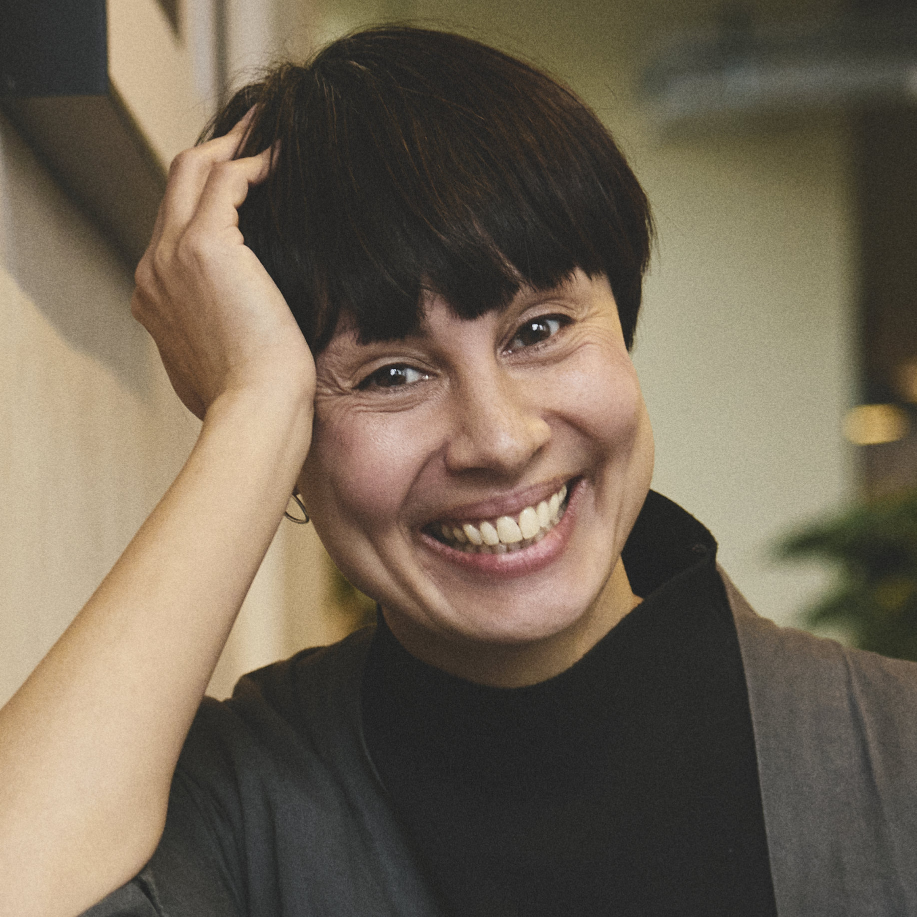 Smiling woman, leans her head on her hand and looks straight at the camera