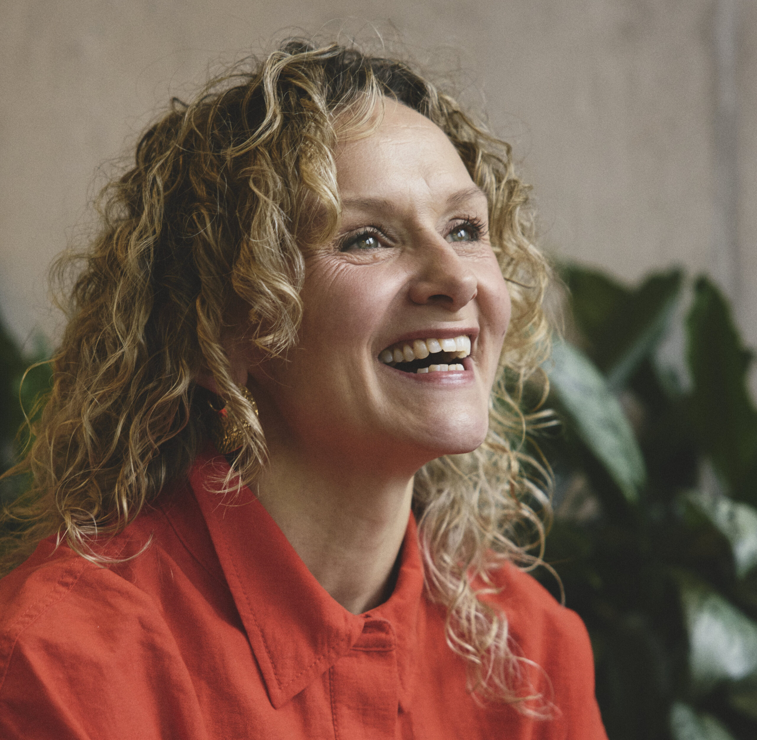 Woman laughs . She wears a bold tomato red shirt