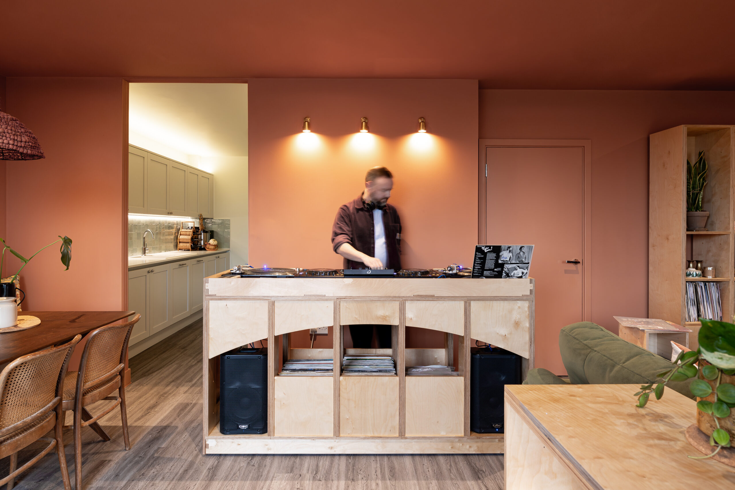 A man djs at a custom built moveable dj booth in a warmly decorated living room. 