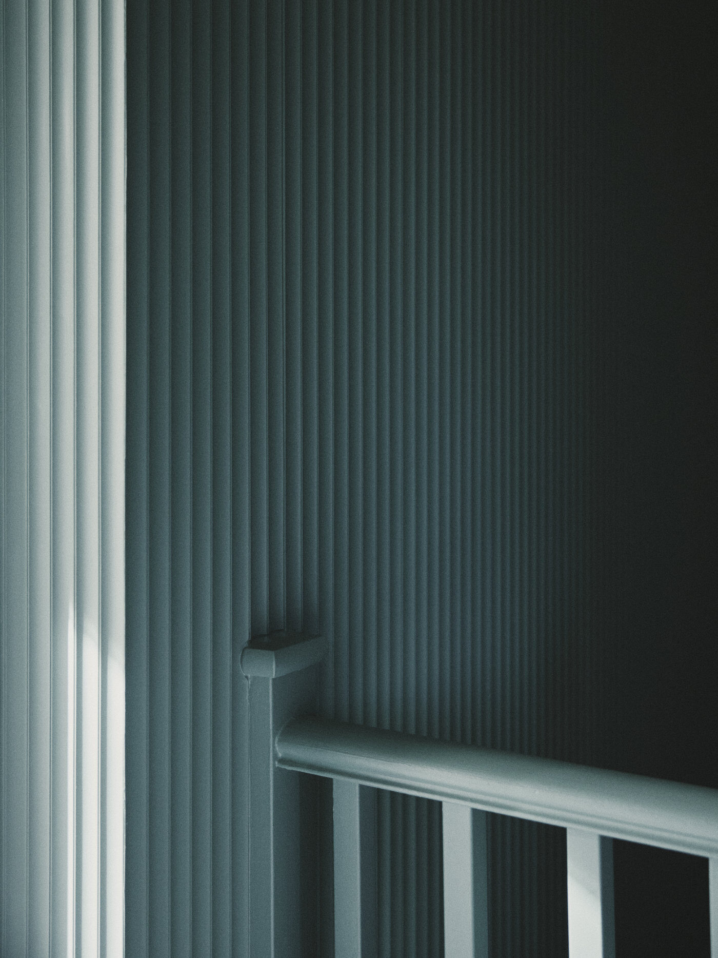 A textured wall at the top of a stiarcase, painted a deep and calming shade of deep green 